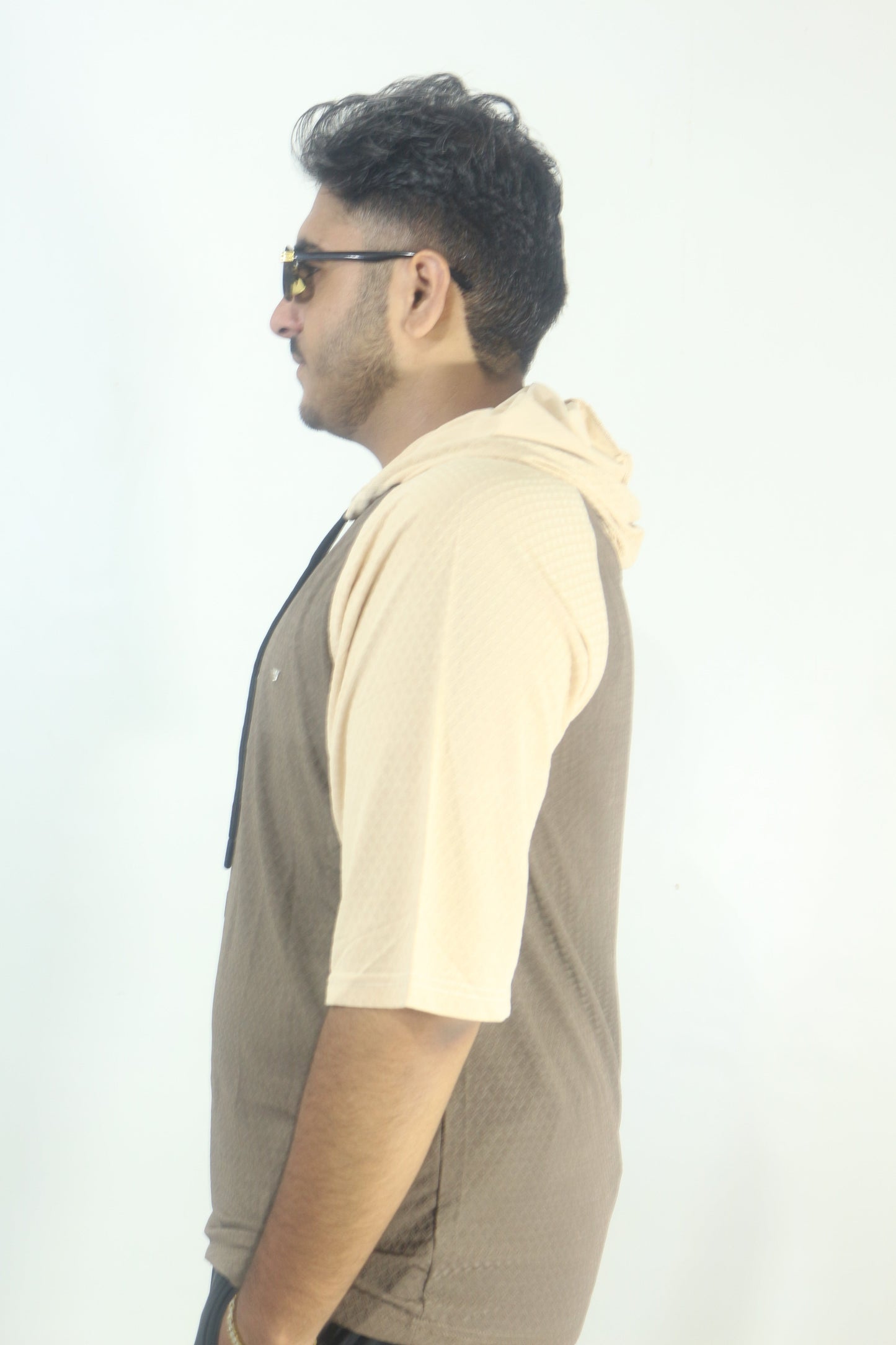 Man wearing a beige shirt and dark pants on a white background