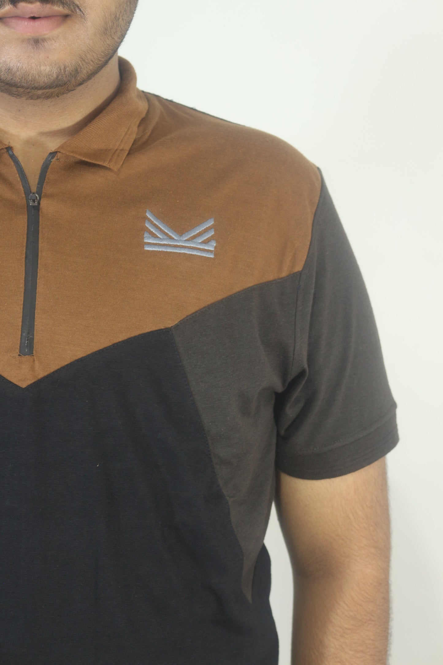 Person wearing a brown and black shirt with a logo on a white background