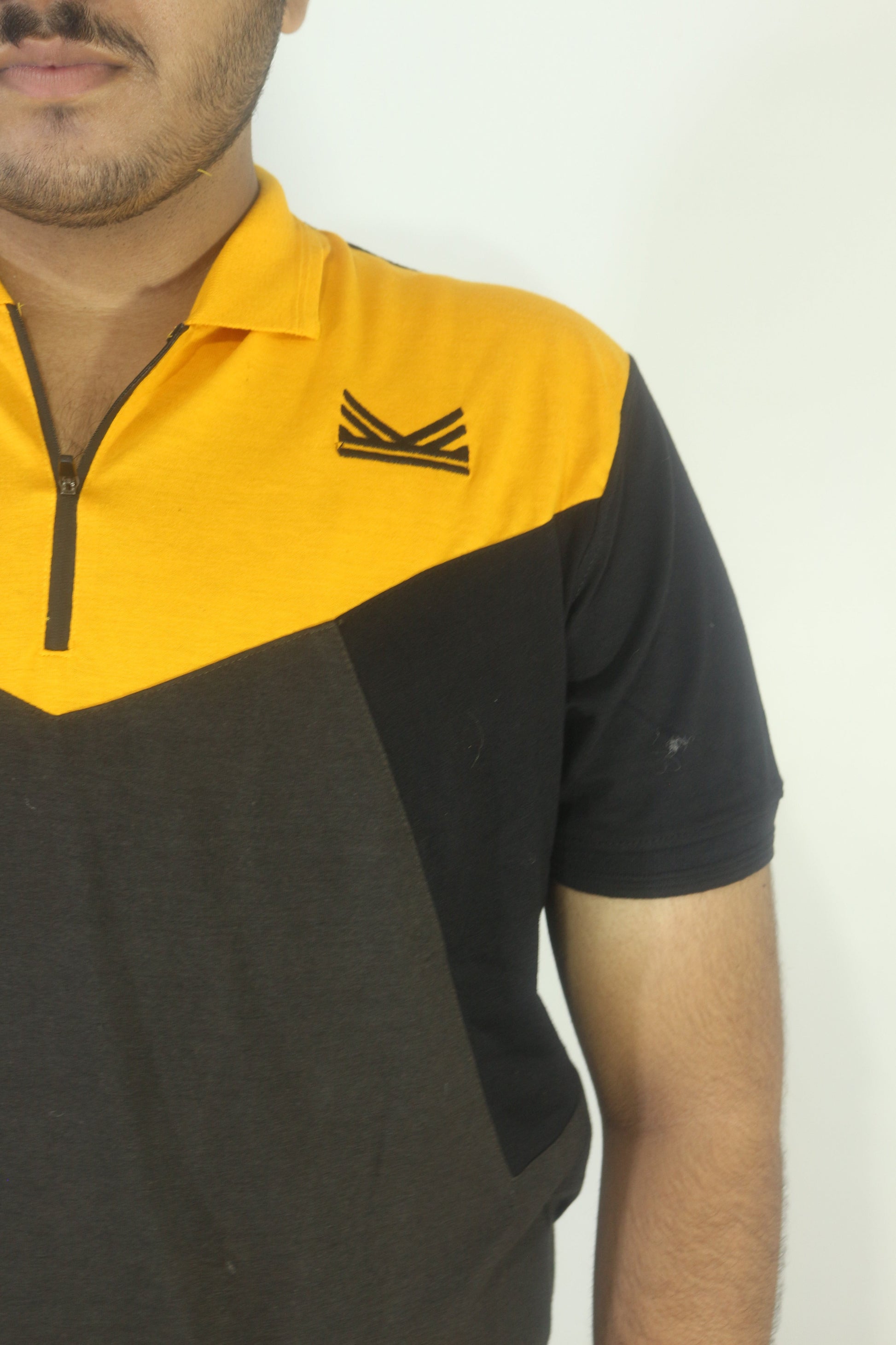 Person wearing a black and yellow shirt with a logo on a white background