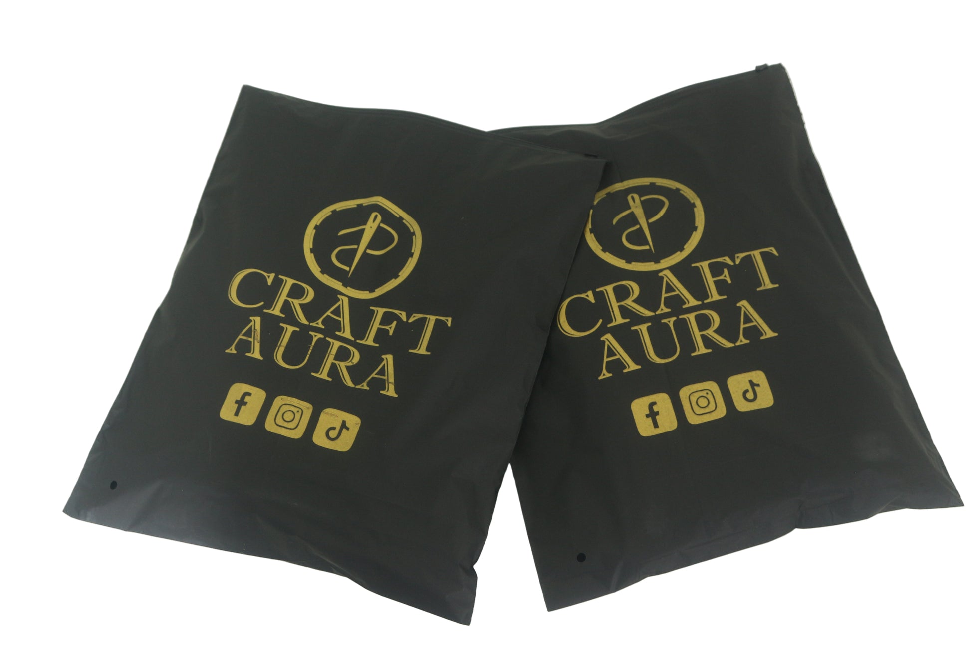 Two black packaging bags with 'Craft Aura' logo and social media icons on a white background